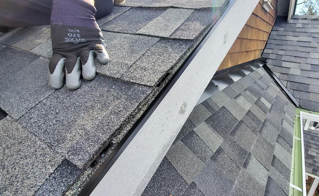 A person wearing gloves is working on a roof from Washington Roofing Services near Arlington WA