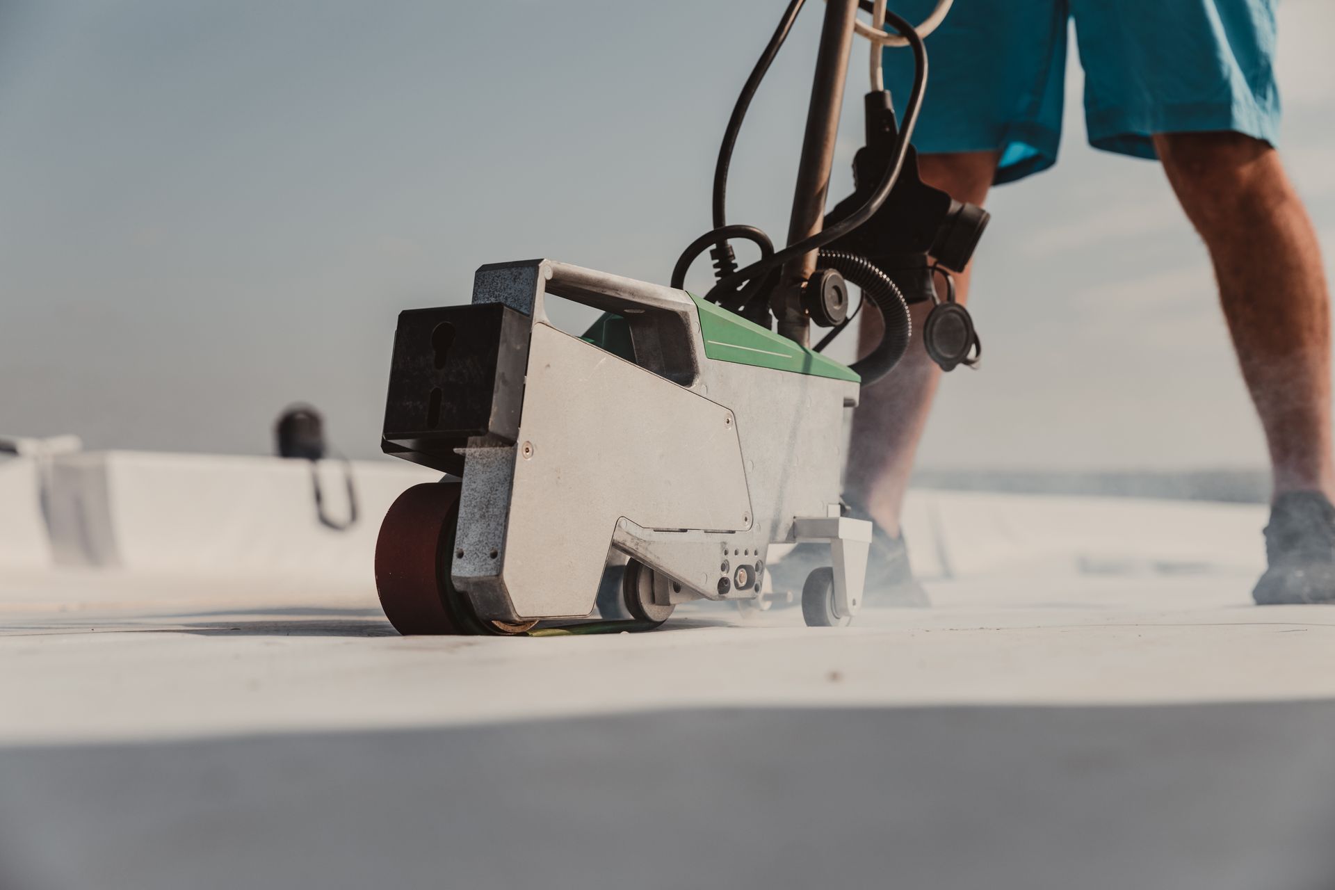 a man is using a machine to seal a roof .